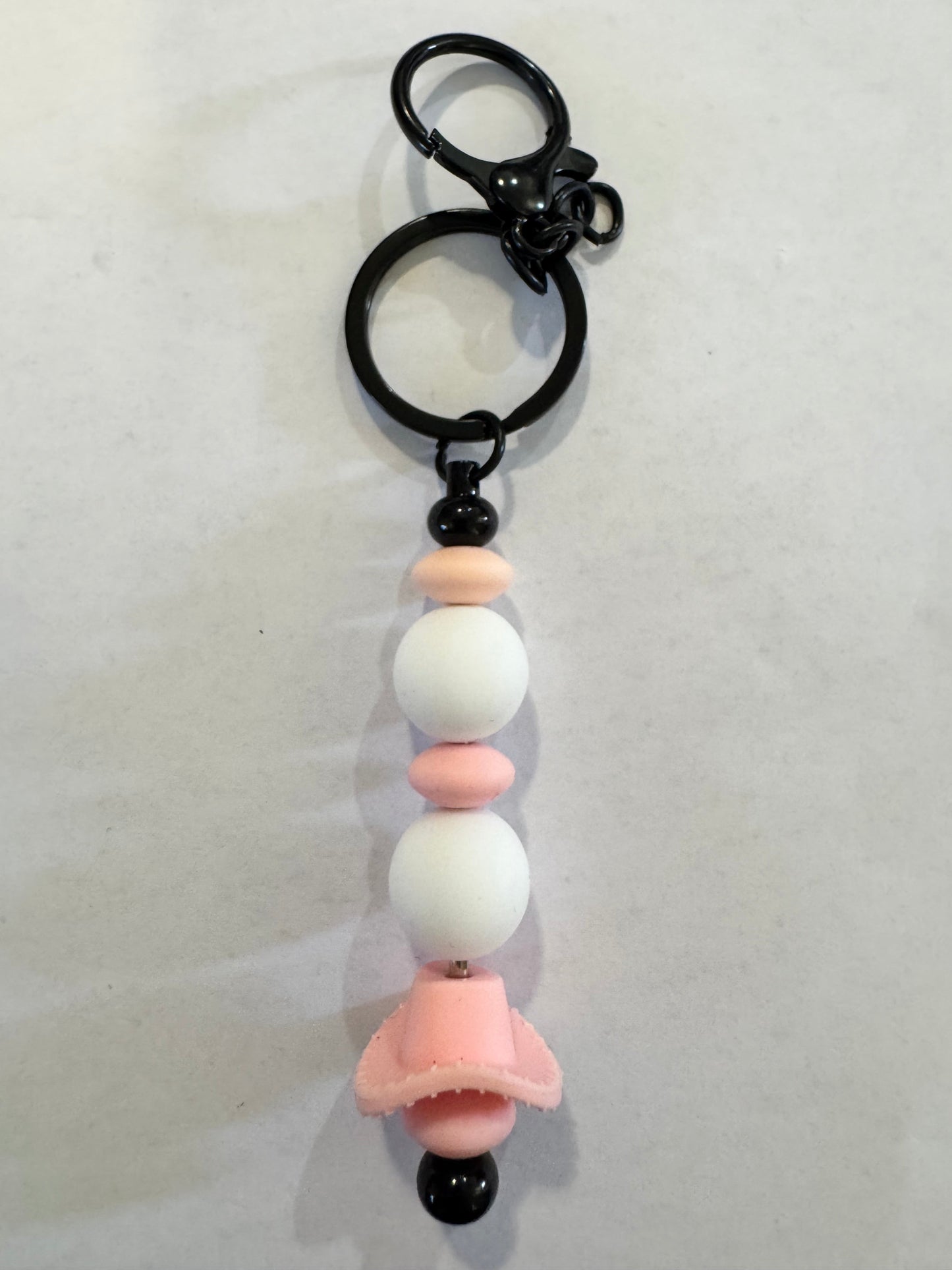 Keychain with beads and a pink flower-shaped charm on a white background