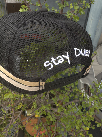 Black mesh cap with 'Stay Dusty' text on a blurred background