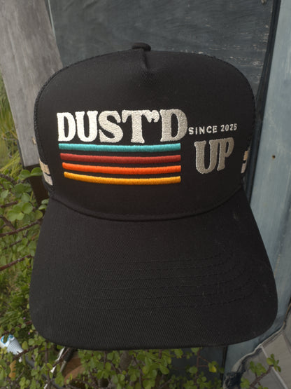 Black cap with 'DUST'D UP' text and colorful stripes on a tent background