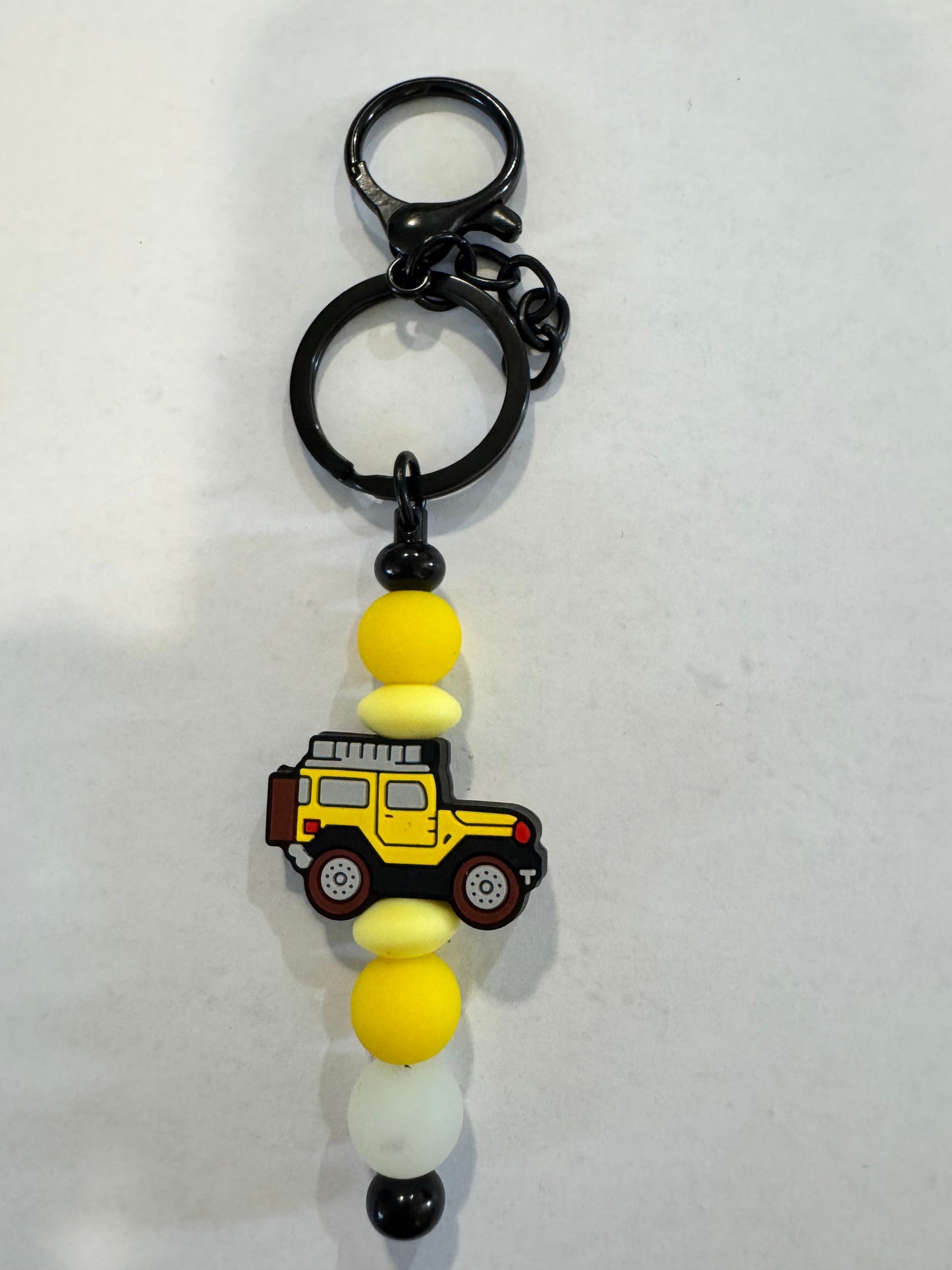 Keychain with a construction JEEP charm and colourful beads on a white background