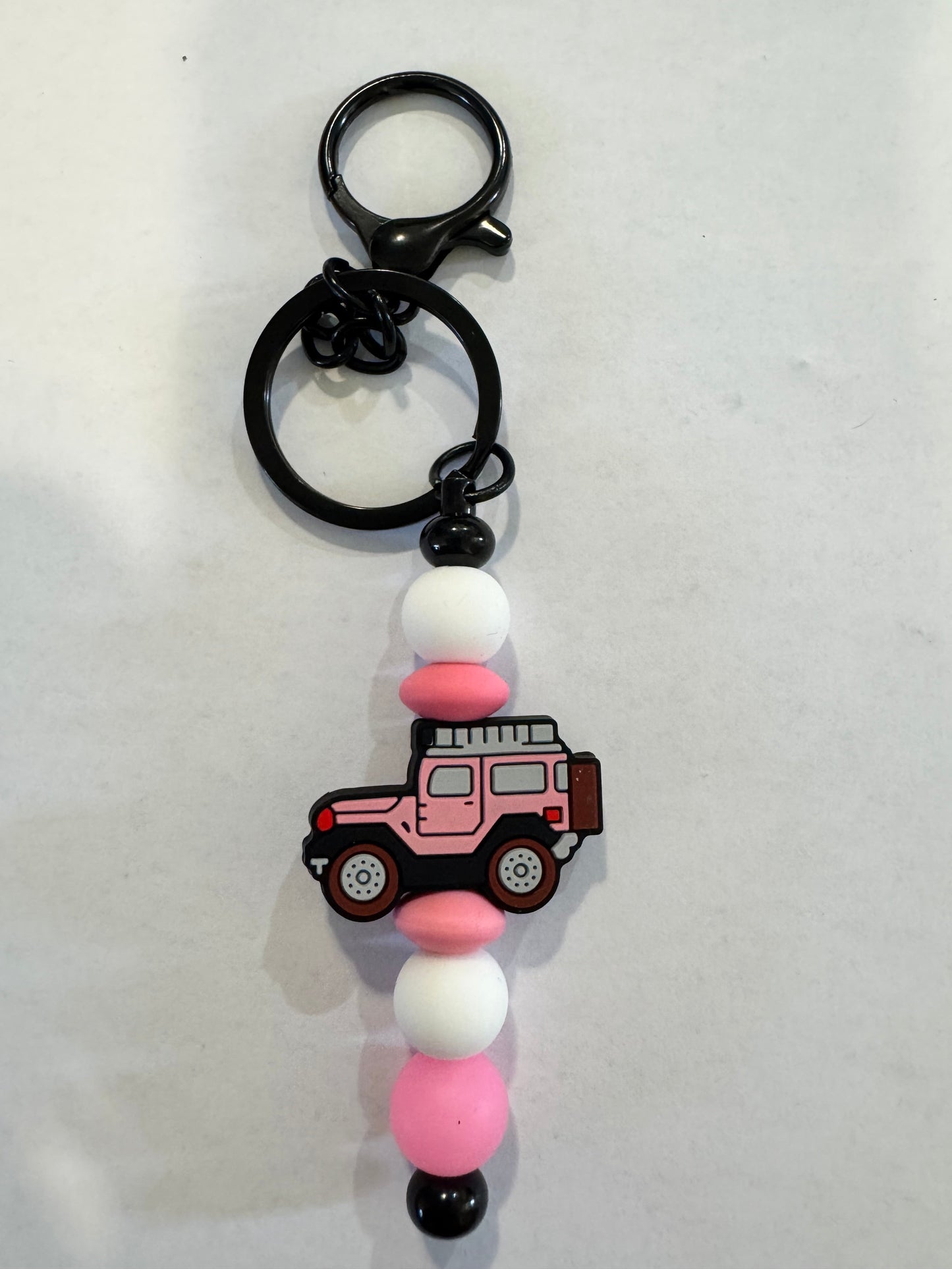 Keychain with pink and white beads and a jeep charm on a light gray background