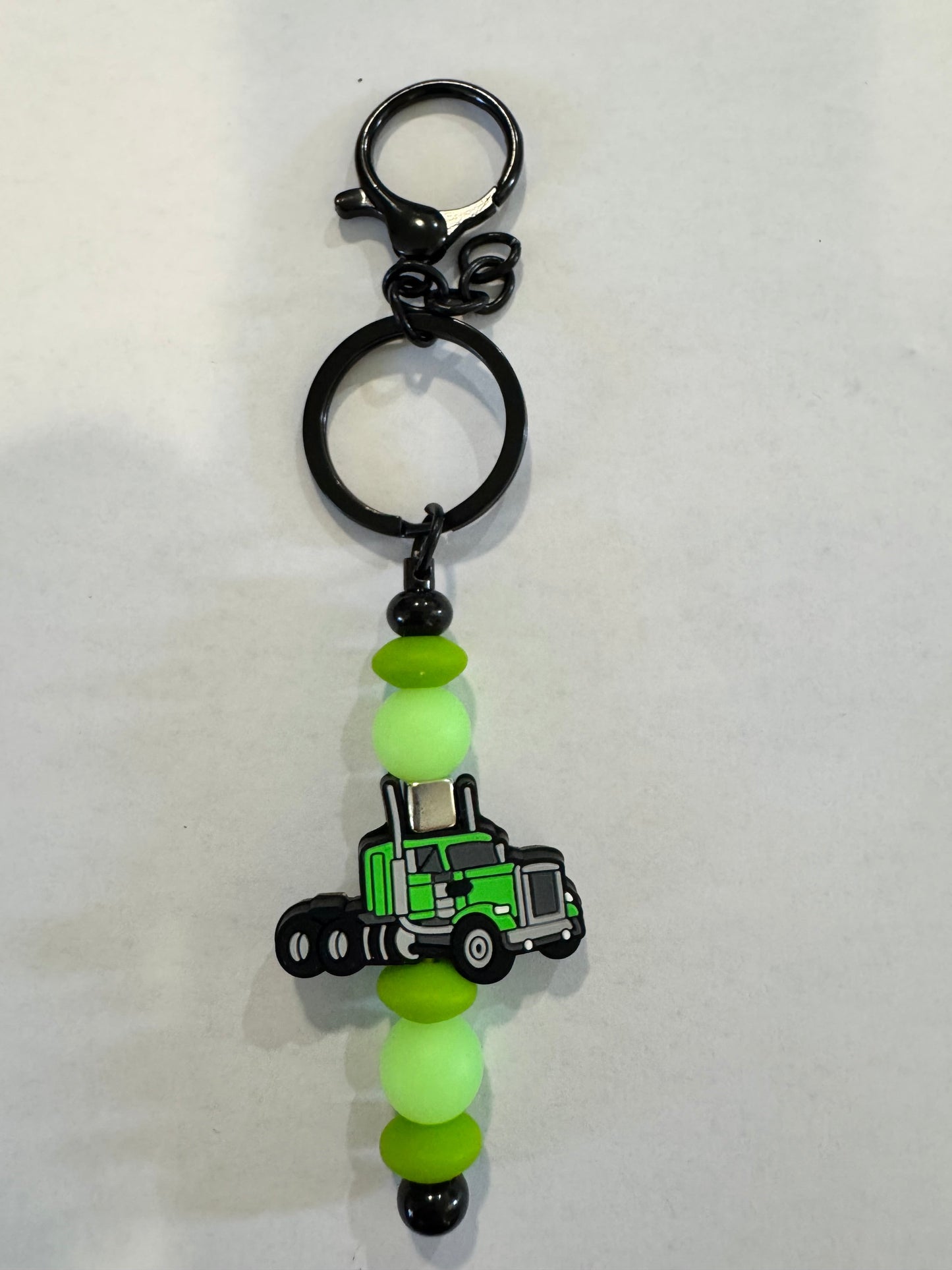 Keychain with green truck charm and beads on a white background