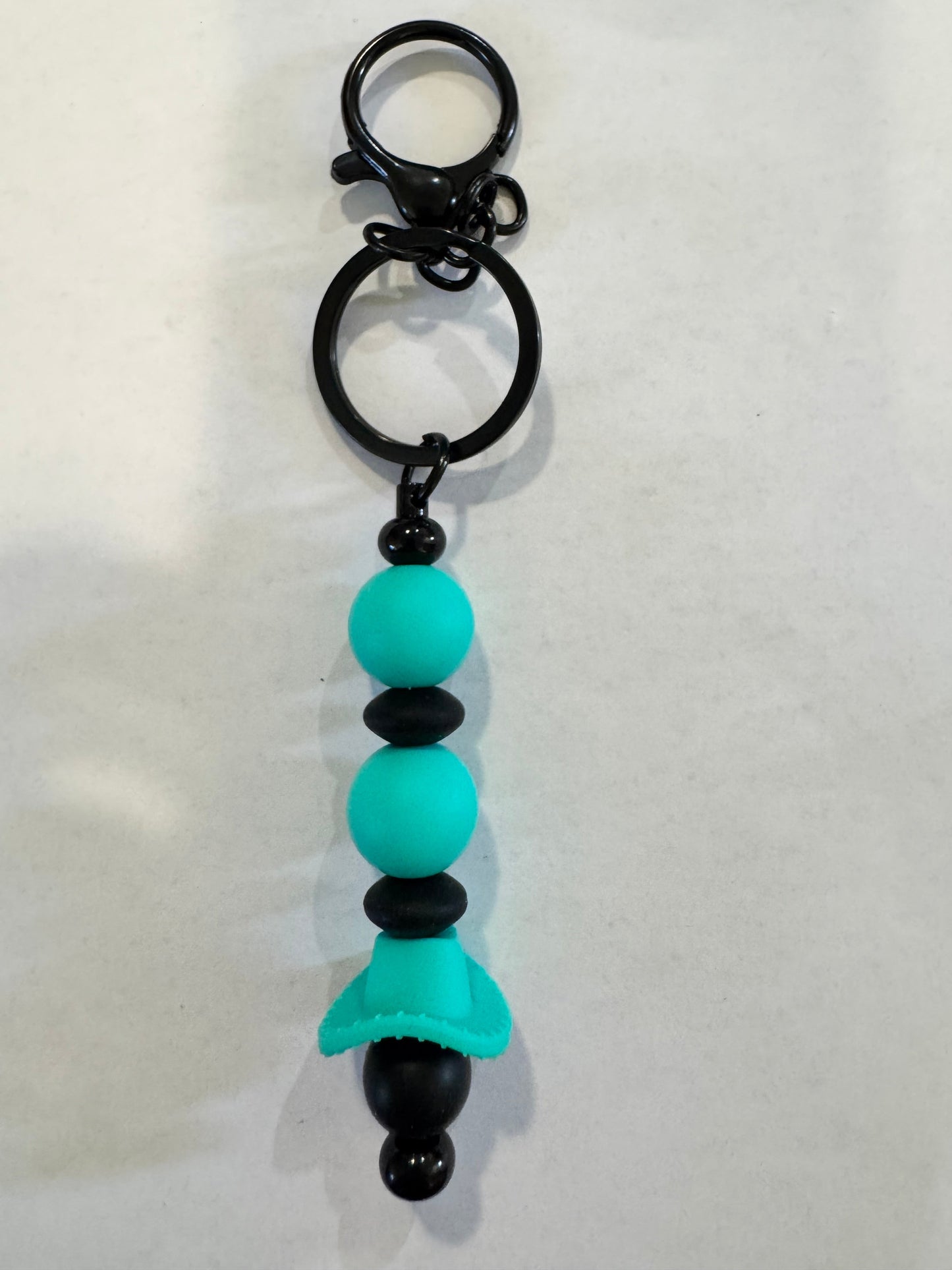 Keychain with turquoise and black beads on a white background