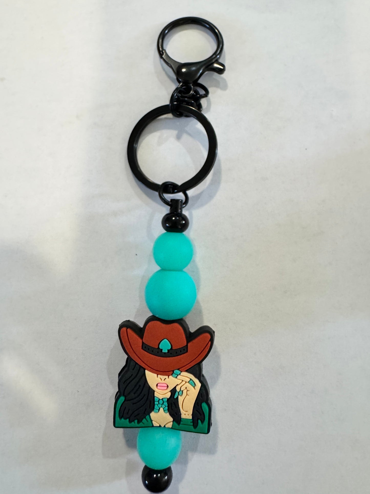 Keychain with cartoon character and turquoise beads on a white background
