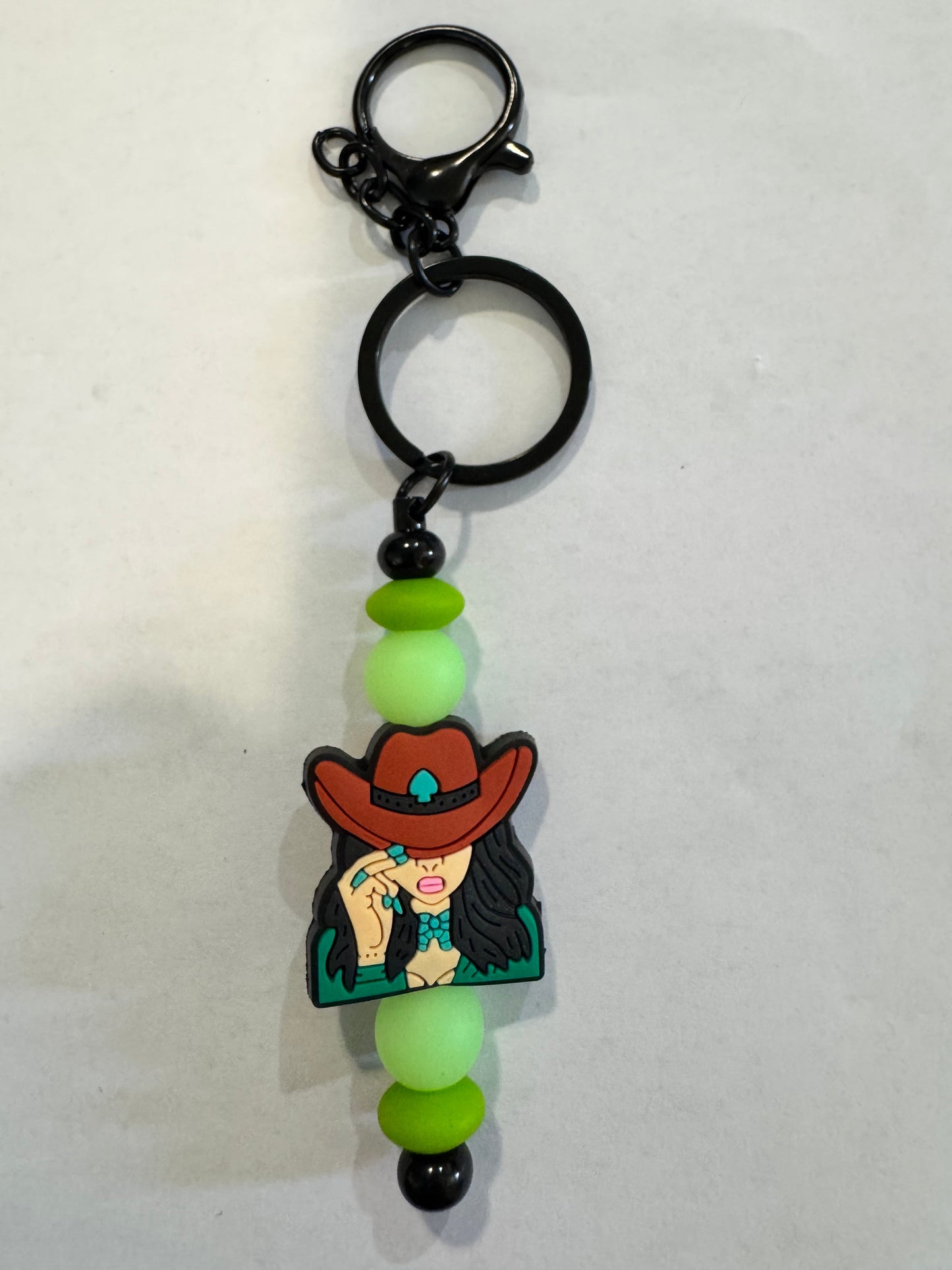 Keychain with cartoon character and green beads on a white background