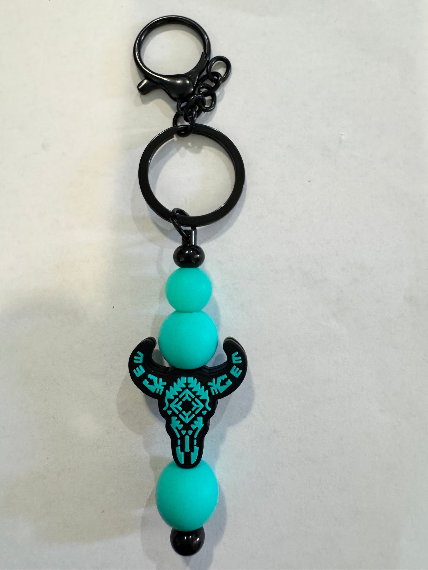 Keychain with turquoise beads and black turtle design on a white background