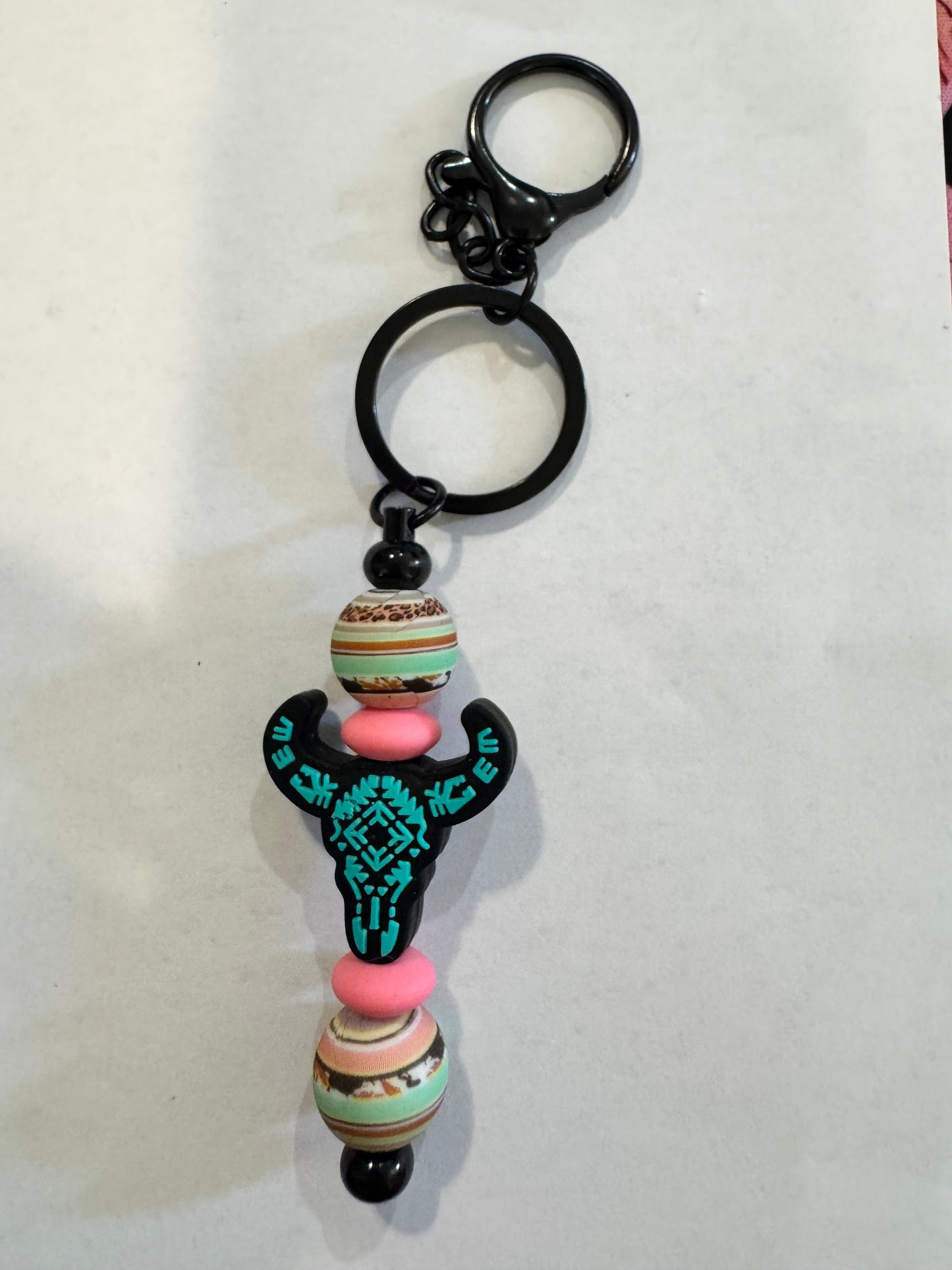 Keychain with colorful beads and a black hand design on a white background