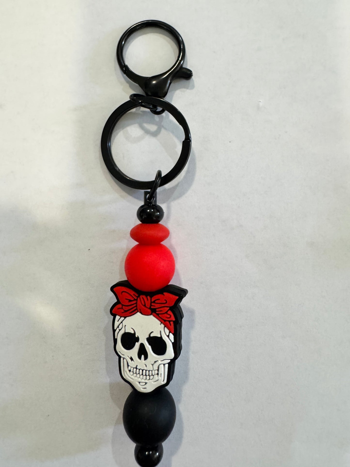 Keychain with skull design and red bead on a white background