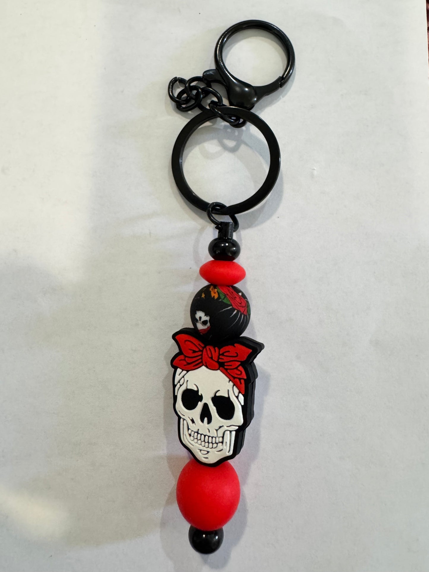 Keychain with skull design and red beads on a white background