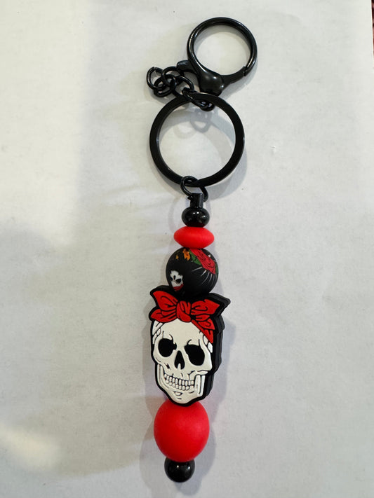 Keychain with skull design and red beads on a white background
