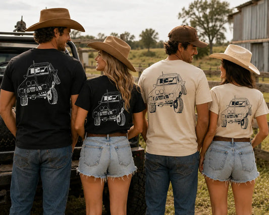 Four people wearing matching t-shirts with a graphic design on a rural background