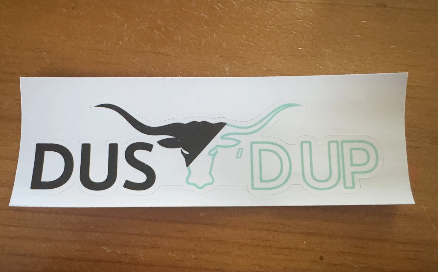 Sticker with DUSt'd up design on a wooden surface